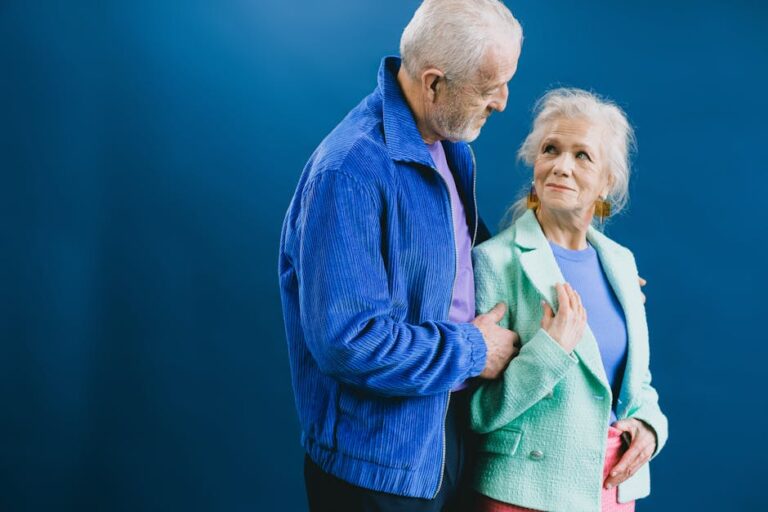 Charming elderly couple sharing a loving moment. Indoor studio setting with vibrant blue backdrop.